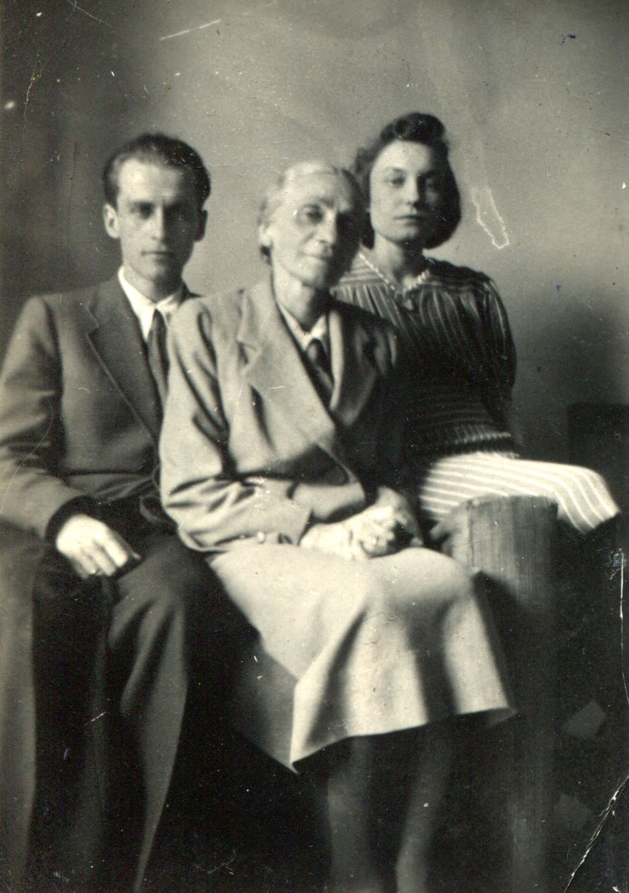 3 osoby siedzące we wnętrzu, w środku siwa kobieta, z boków 21-letni mężczyzna i 20-letnia kobieta