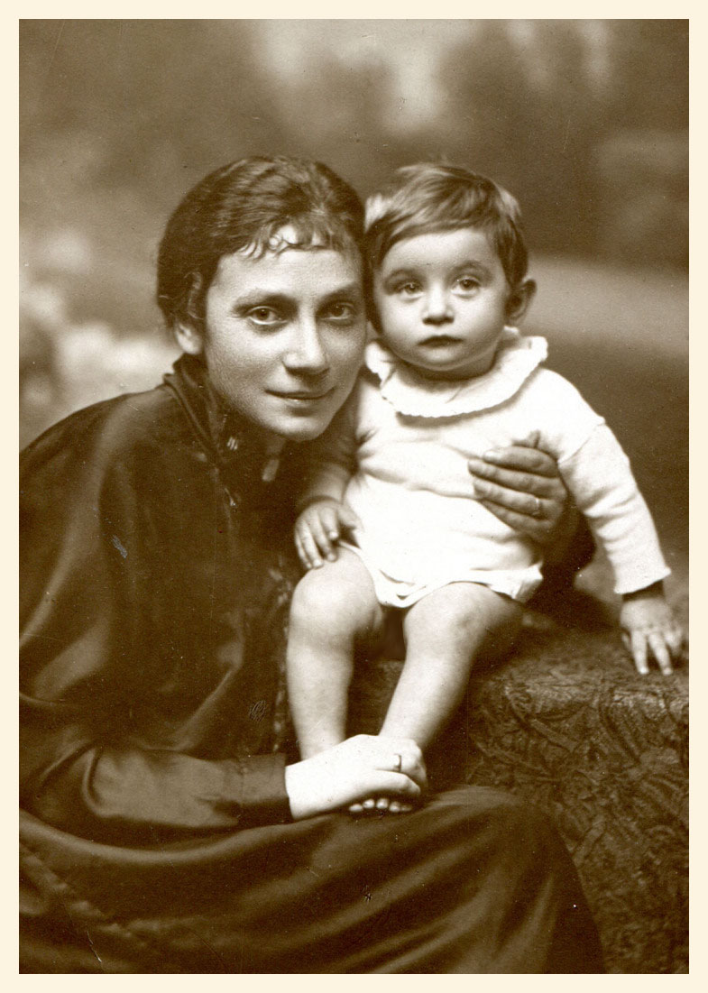 Siedząca młoda kobieta, trzymająca chłopczyka około roku, ubranego w koszulkę i z gołymi nóżkami