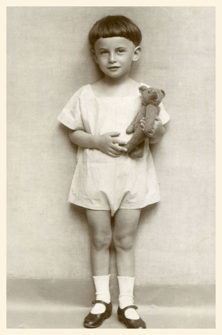 Stojący chłopczyk około 4 lat, widoczny w całej postaci, z pluszowym misiem w rękach