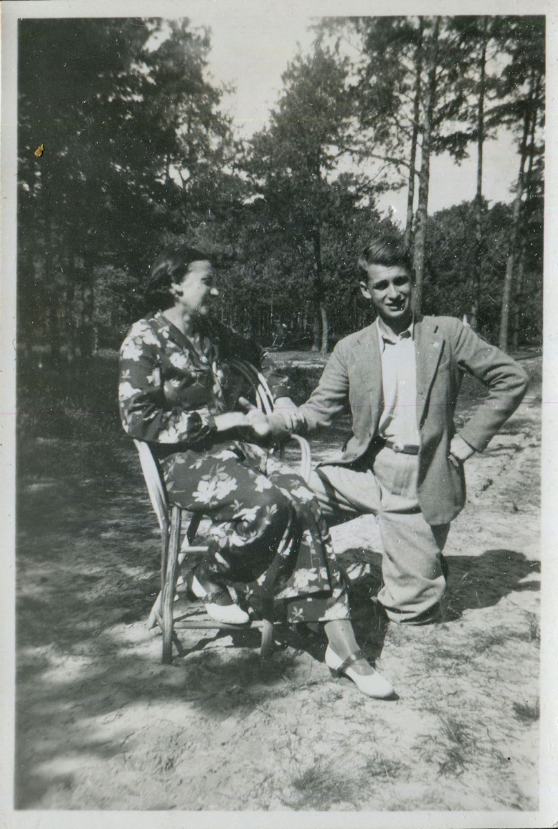 Na leśnej polanie kobieta na krześle i klęczący na jedno kolano chłopak około 15, podający jej dłoń