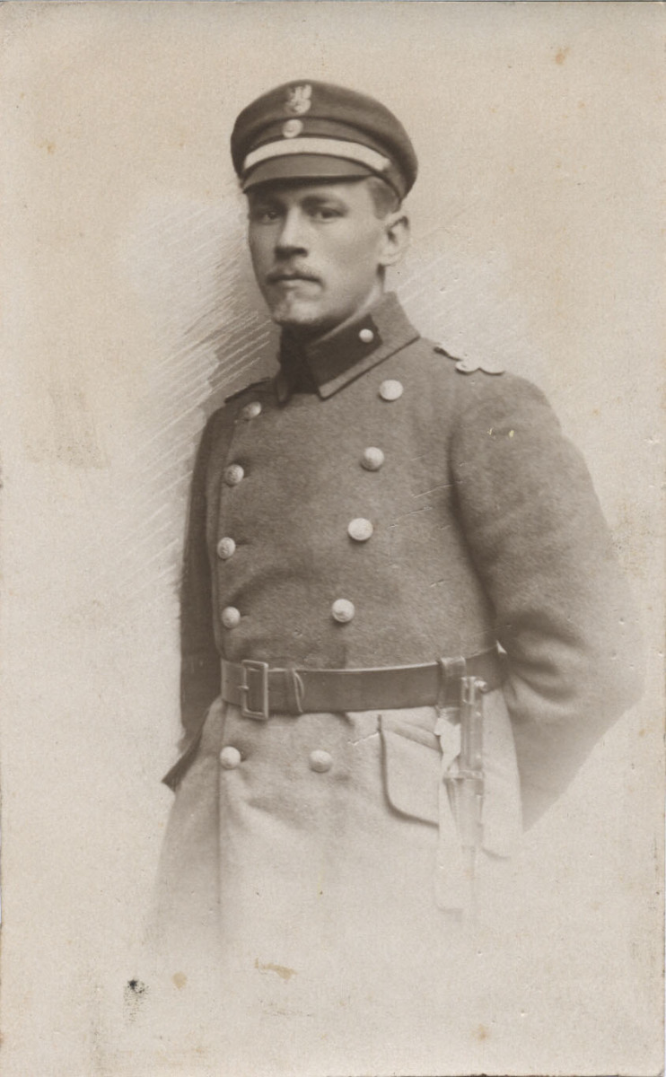 Żołnierz około 30 lat w mundurze i czapce z orzełkiem. Ujęcie ¾ w lewo, spojrzenie na wprost