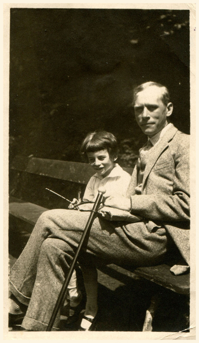 Uśmiechnięty chłopiec około 7 i młody mężczyzna, siedzący obok siebie na ławce w parku