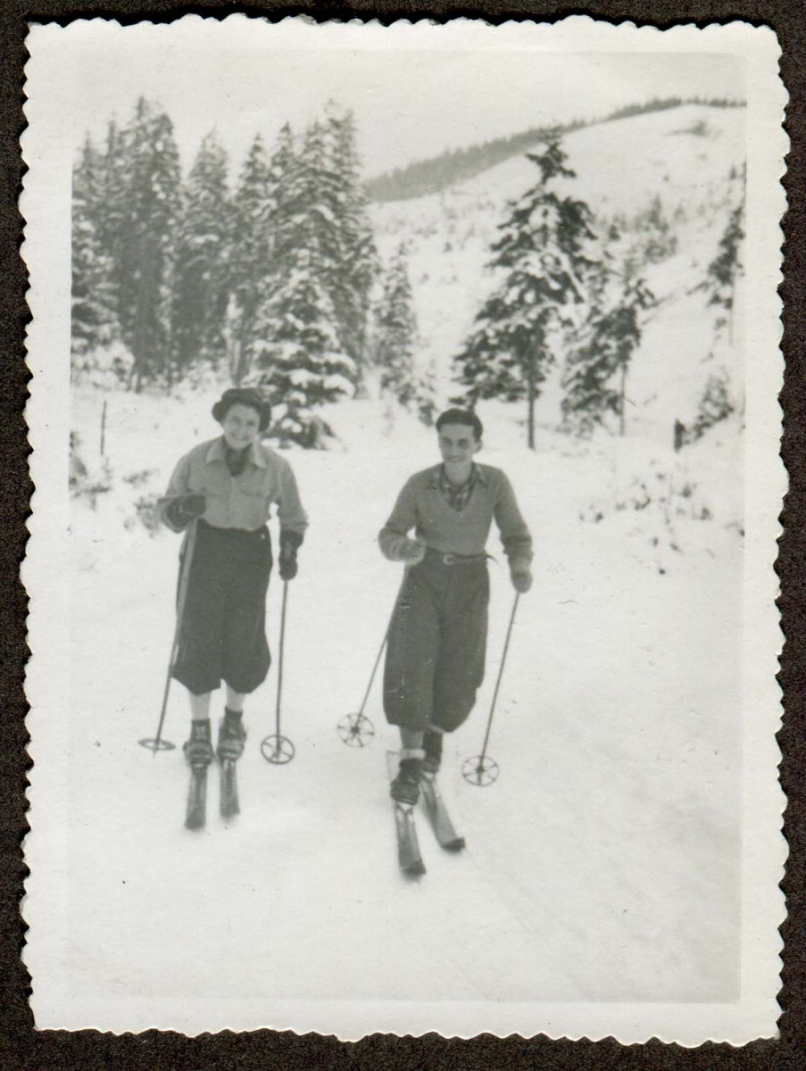 Dziewczyna i chłopak około 18 lat, stojący na nartach na tle ośnieżonych gór i świerków