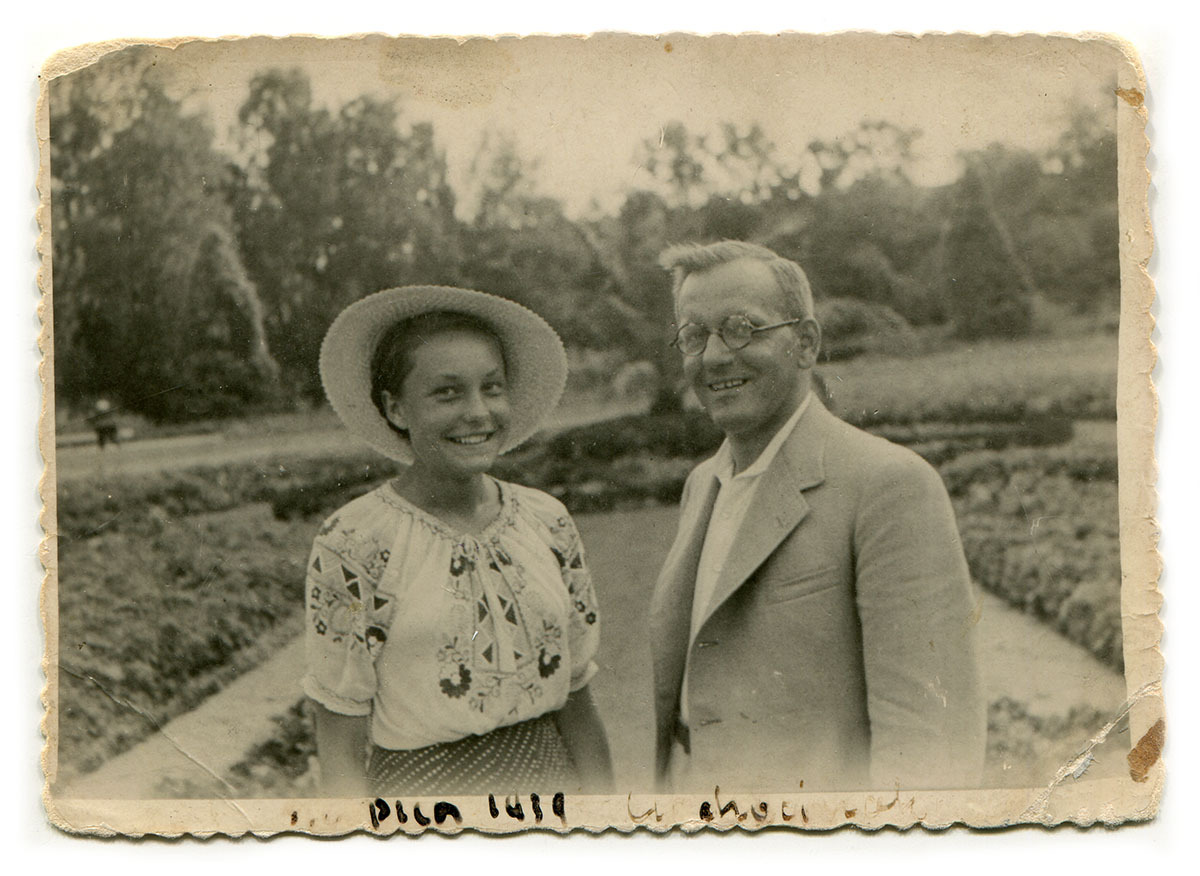 Czarno-biała fotografia dziewczyny i mężczyzny, uśmiechniętych, stojących obok siebie w parku