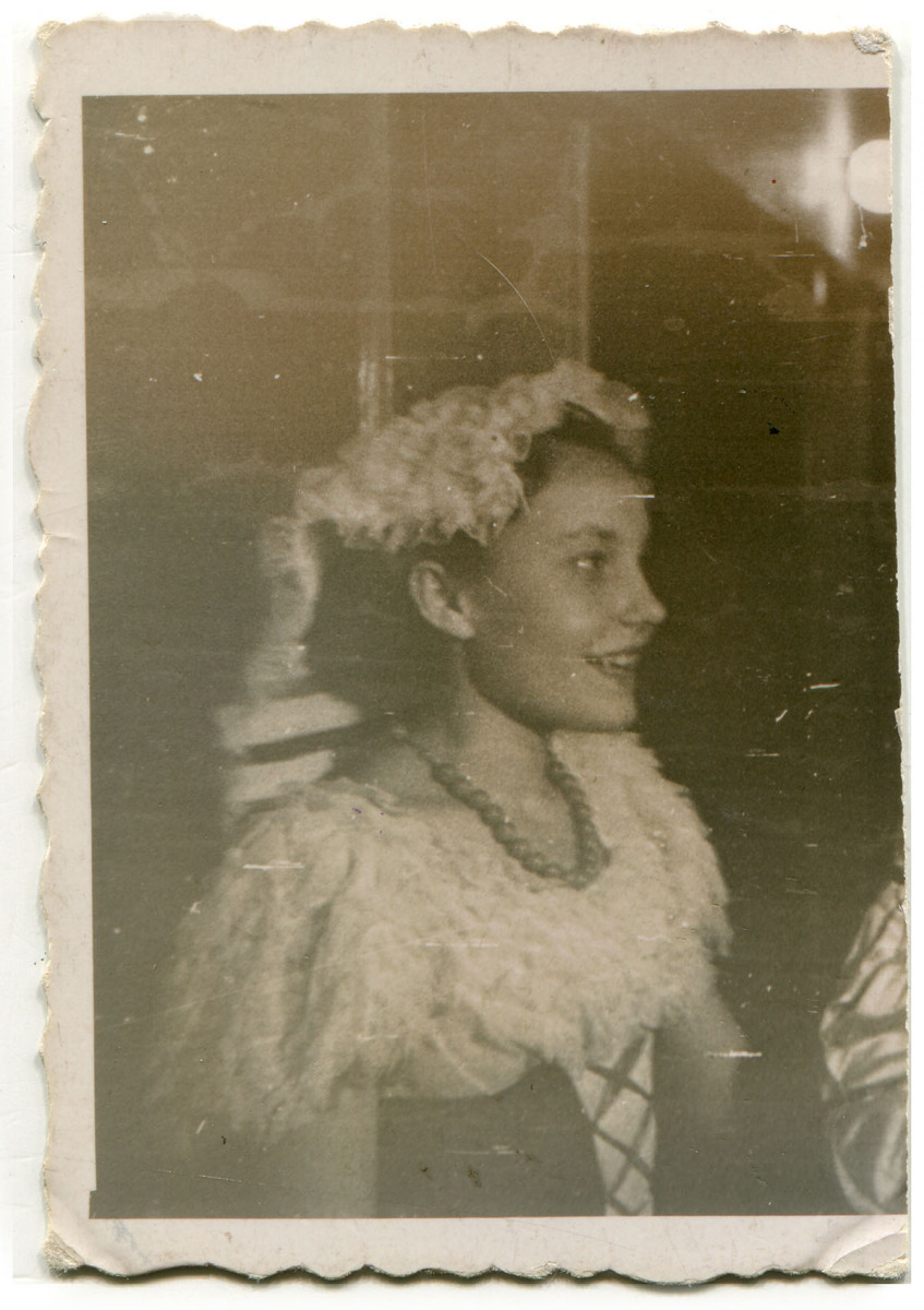 Ukazana z profilu uśmiechnięta dziewczynka, przebrana w karnawałowy kostium