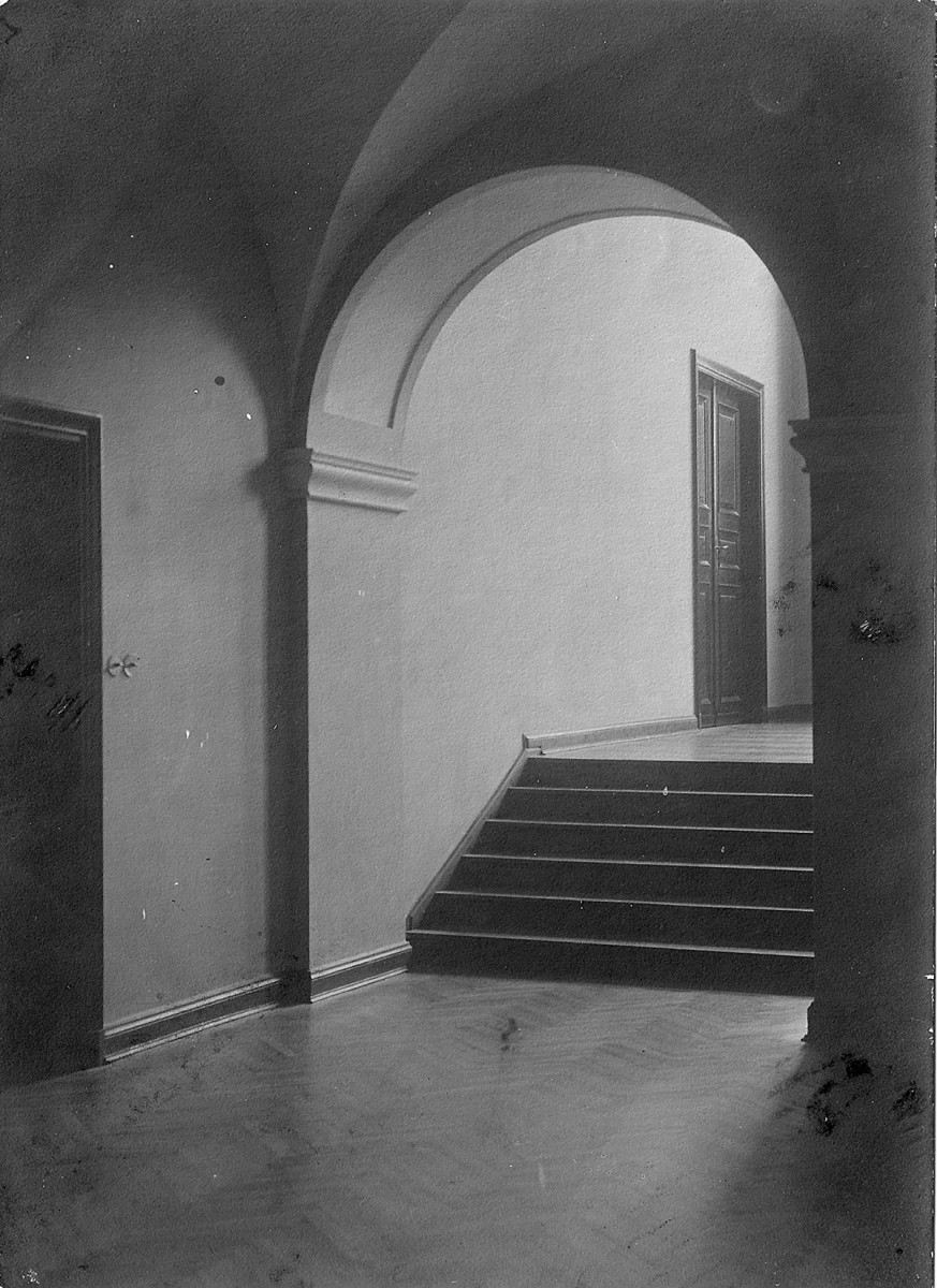Pusty korytarz pod sklepieniem łukowym, ze schodkami prowadzącymi na półpiętro