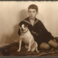 Chłopiec około 12 lat, siedzący na podłodze z pieskiem kundelkiem o jasnej sierści i ciemnych uszach