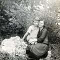 Ośmioletni chłopiec, siedzący z matką na kamieniu wśród krzewów i przytulający się do niej