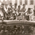 Uczniowie na brzegu ocembrowanego stawu, z tabliczkami z nazwami gatunków, strojący głupie miny